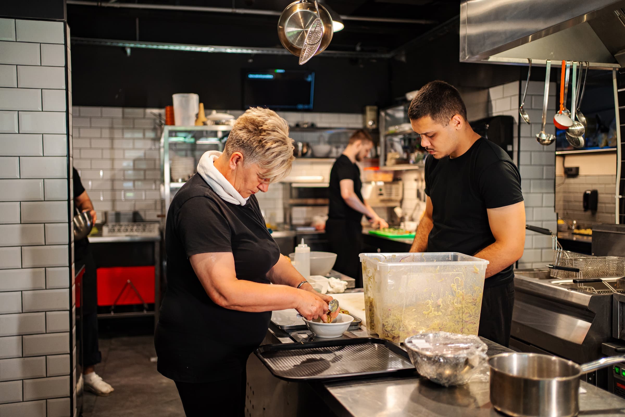 Equipo de cocina preparando platos durante el servicio en un restaurante.
